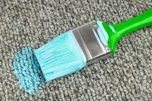 paint brush with blue paint on carpet