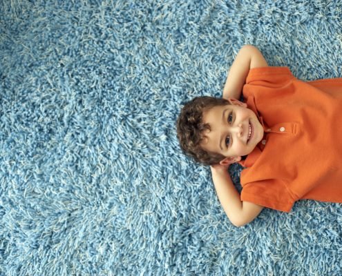 boy laying on blue carpet