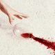 Womans hand reaching for spilled glass of red wine on carpet